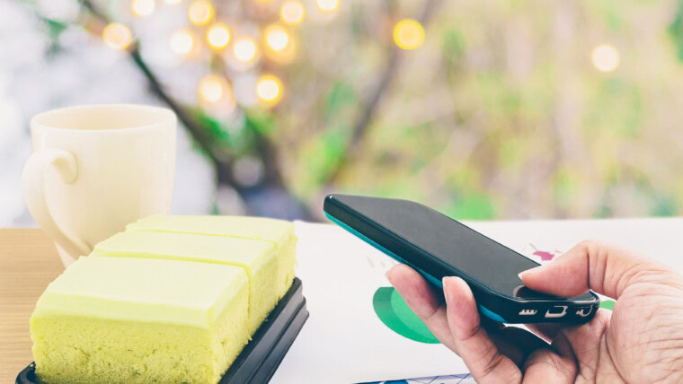 Zbliżenie osoby trzymającej telefon komórkowy na stole