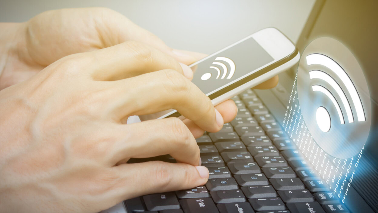 Przycięte ręce człowieka używającego telefonu komórkowego z symbolem wifi