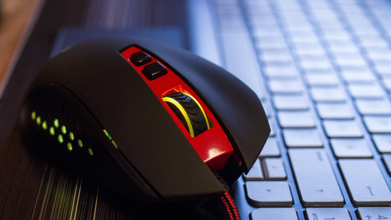 Zbliżenie czerwonej i czarnej myszy komputerowej na klawiaturze laptopa na stole