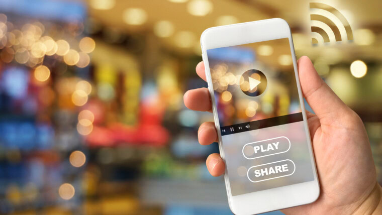 Zbliżenie ręki trzymającej smartfon przeciwko oświetlonym światłom