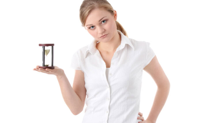 Portrait of smiling young woman holding hourglass against white background