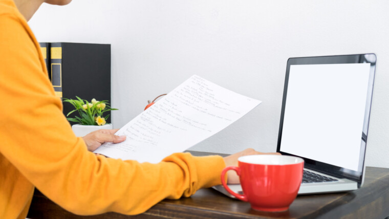 Środkowa sekcja bizneswoman używając laptopa podczas trzymania dokumentu na stole