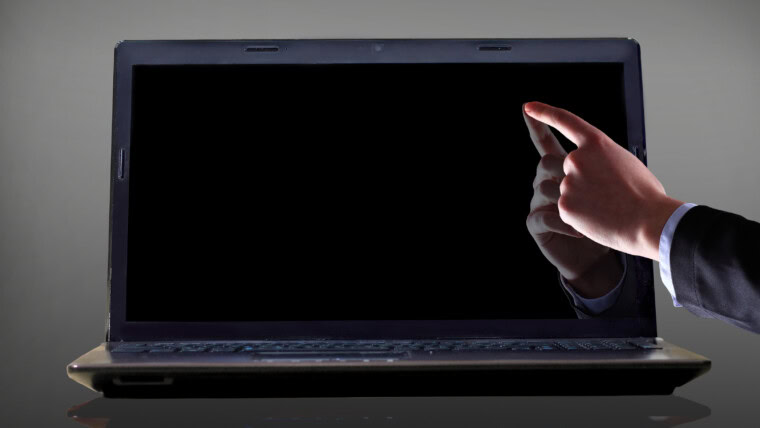 Zbliżenie: męskiej dłoni z palcem wskazującym, wskazując na ekranie laptopa na czarnym tle