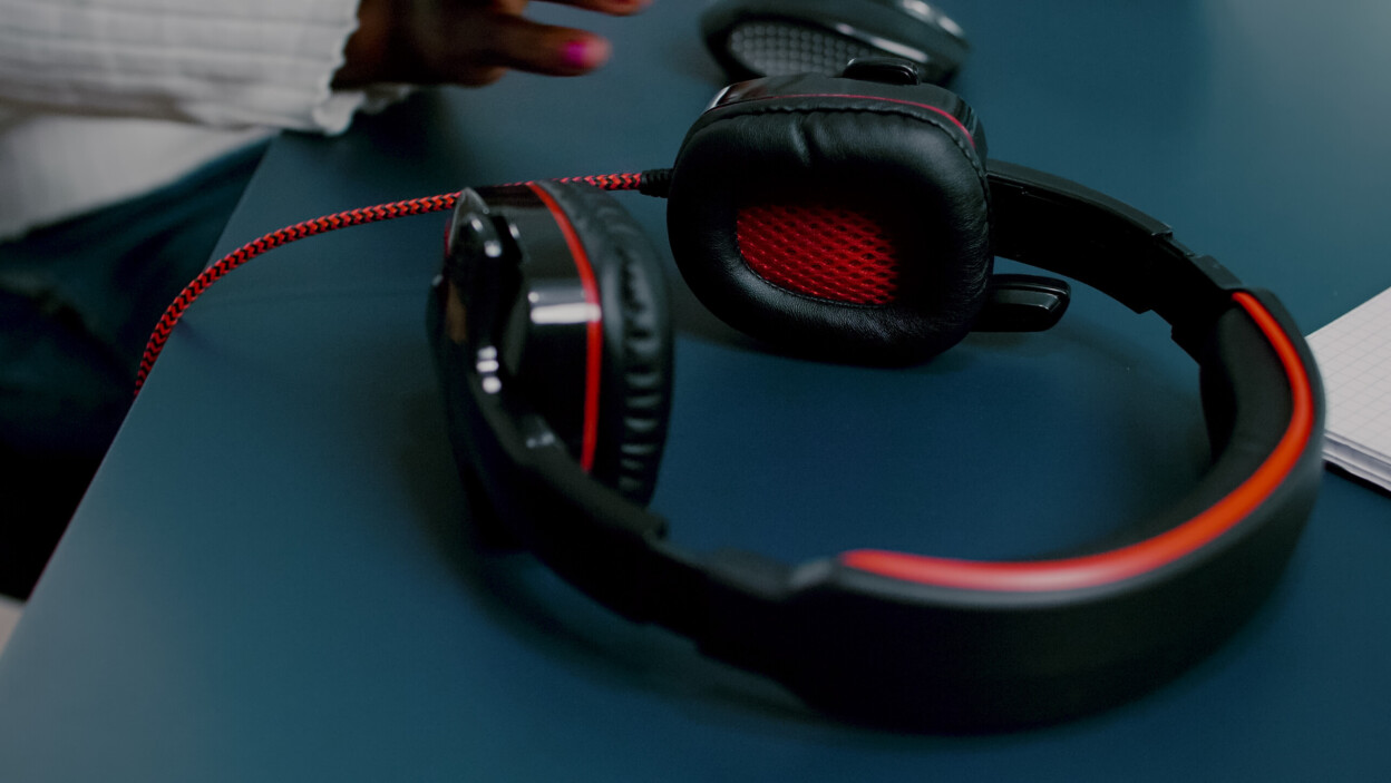 Czarny edytor wideo pracujący z materiałem na PC z dwoma monitorami zakładającymi słuchawki african videog...