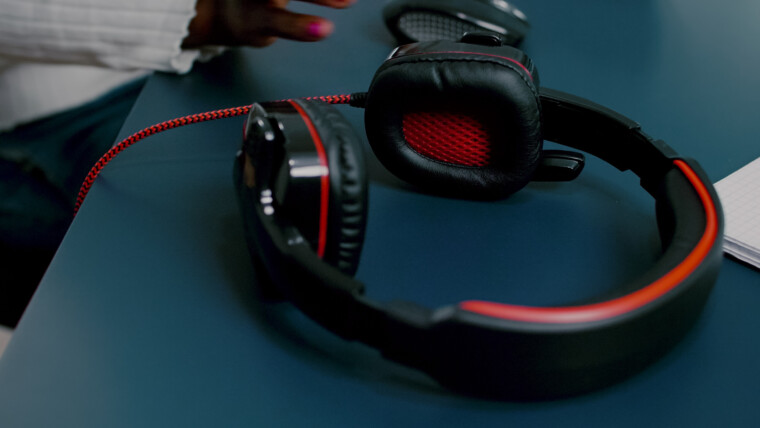 Czarny edytor wideo pracujący z materiałem na PC z dwoma monitorami zakładającymi słuchawki african videog...