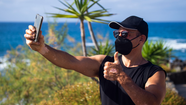 Sportowiec na plaży robi selfie z założoną maską