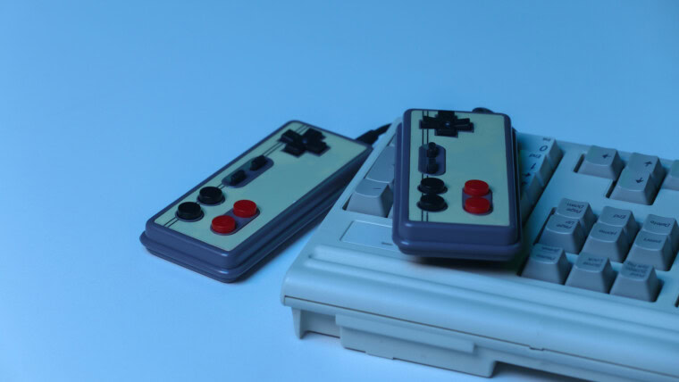 Stara klawiatura komputerowa z gamepadami w niebieskim świetle holograficznym. Retro fala