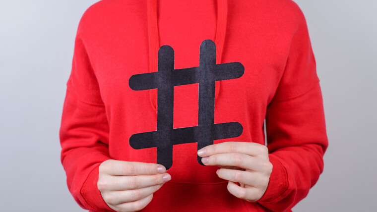 Marketing internetowy koncepcja sprzedaży tweet dla młodzieży. Przycięte zbliżenie zdjęcie wesoły pozytywny zadowolony optymistyczny uśmiech toothy młodzieniec trzymający duży duży czarny hashtag w dłoni na białym tle szarym
