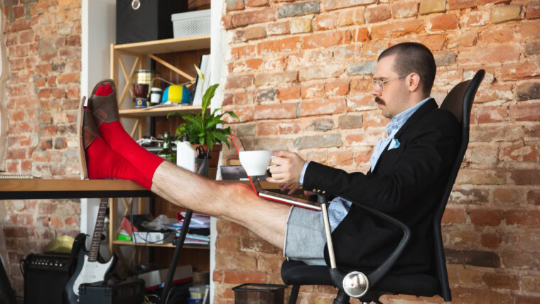 Przewijanie. Młody człowiek bez spodni, ale w kurtce, pracujący na komputerze, laptopie. Zdalne biuro podczas koronawirusa, zabawne i wygodne w majtkach. Izolacja, kwarantanna, humor, koncepcja biznesowa.