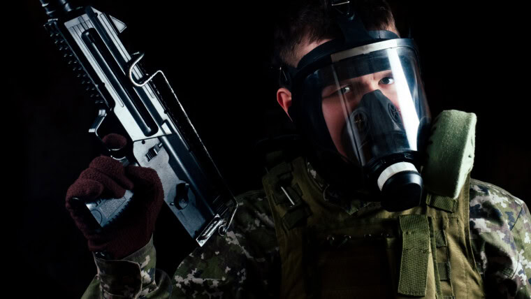 Mężczyzna terrorysta w masce gazowej trzymający pistolet na czarnym tle.