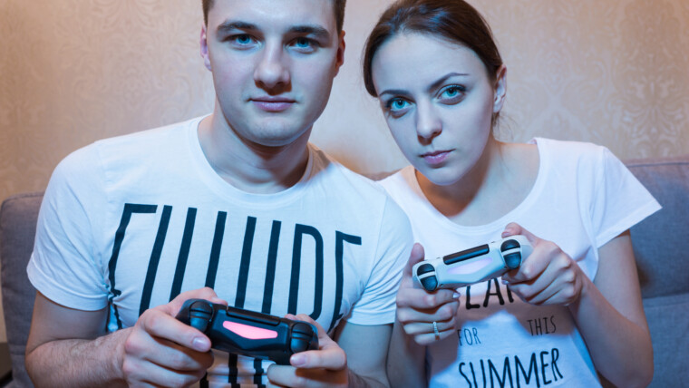 Portret młodej i atrakcyjnej pary chłopca i dziewczyny grających w gry wideo siedzących na kanapie przed telewizorem w domu w miłej atmosferze