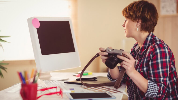 Skupiający się fotograf patrzeje fotki na jej komputerze