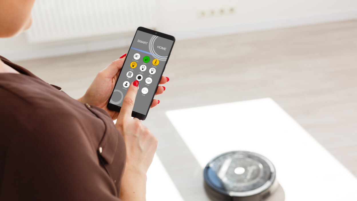 Ręczne sterowanie robotem odkurzającym na podłodze z laminatu drewnianego.