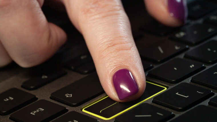Zbliżenie na palec kobiety, naciskając przycisk Enter na klawiaturze laptopa.