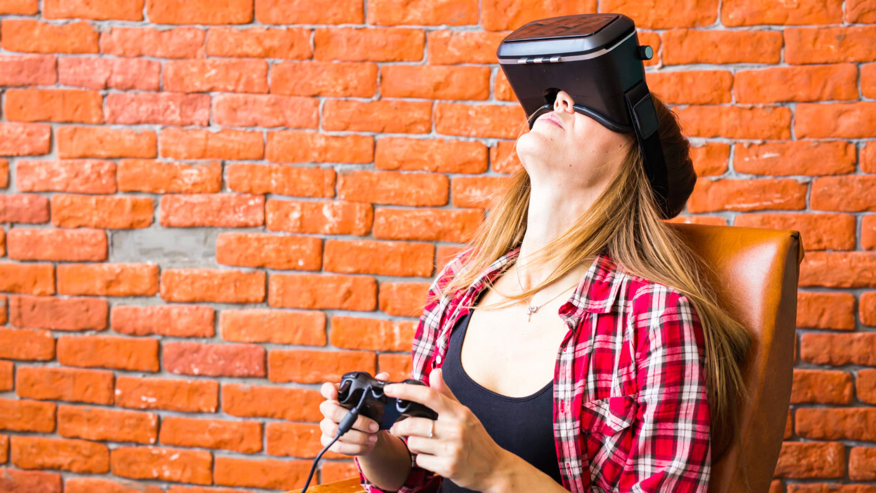 Kobieta gra w grę wideo za pomocą joysticka z urządzeniem VR