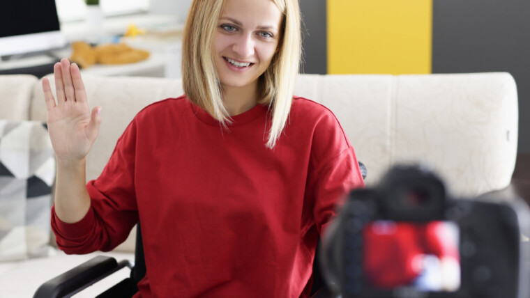 Młoda kobieta gra na pianinie i macha do kamery w domu