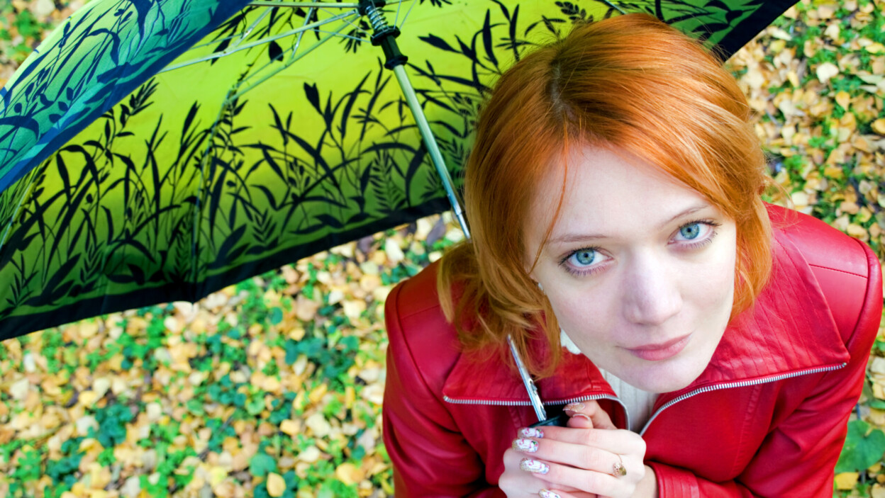 Piękna czerwona dziewczyna w skórzanej kurtce z parasolem