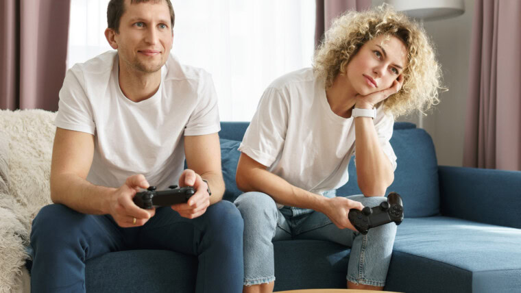 Młoda szczęśliwa para z gamepadami gra w konsolę do gier