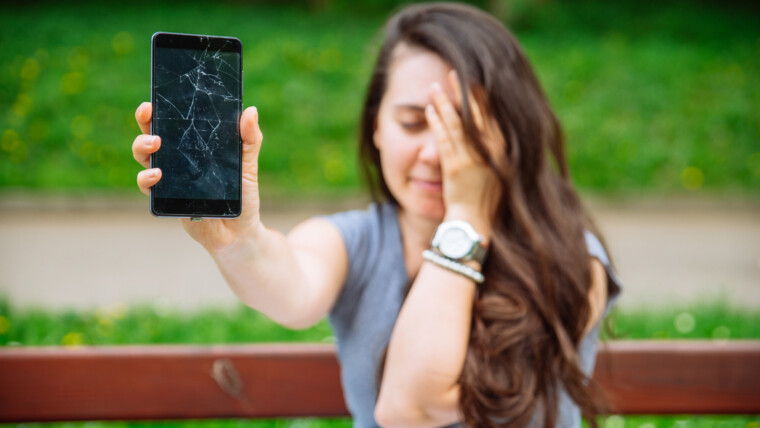 smutna młoda dorosła kobieta pokazująca pęknięty telefon