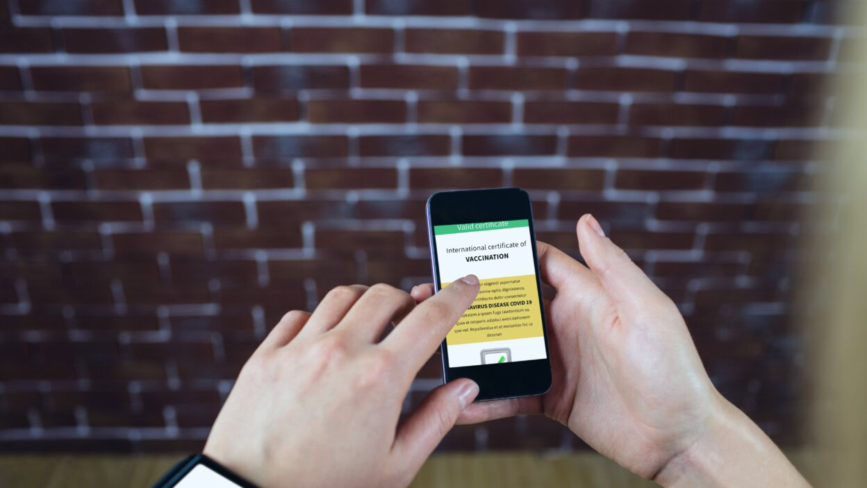 Skład kobiety trzymającej smartfon z międzynarodowym świadectwem szczepienia Covid 19