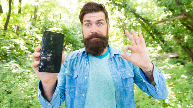 Wędrówka z aplikacją nawigacyjną Trasa dla ekscytującej przygody Aplikacje GPS i do nawigacji Przydatny program Nawigacja online na smartfonie Brodaty wędrowiec spacerujący po lesie z aplikacją nawigacyjną