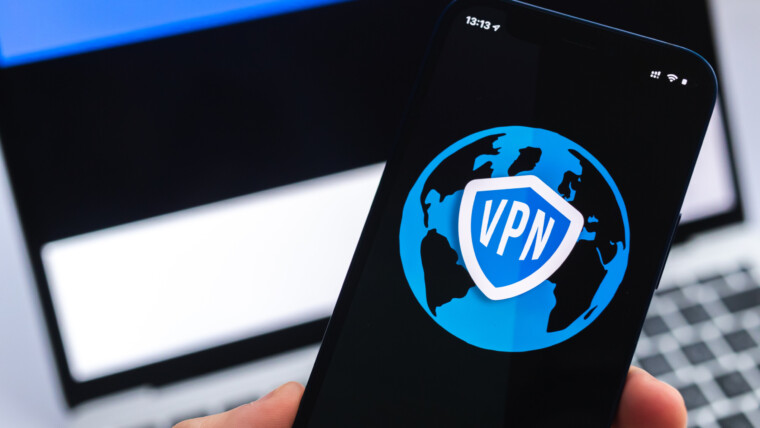 VPN w Estonii Koncepcja bezpiecznego i bezpiecznego internetu Prywatność Ręka z telefonem komórkowym i aplikacją VPN Flaga i laptop na zdjęciu w tle