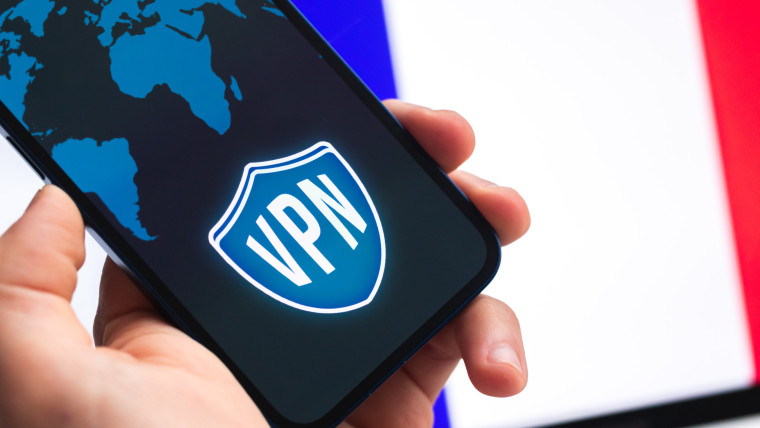 VPN we Francji Koncepcja bezpiecznego i bezpiecznego internetu Prywatność Ręka z telefonem komórkowym i aplikacją VPN Flaga i laptop na zdjęciu w tle