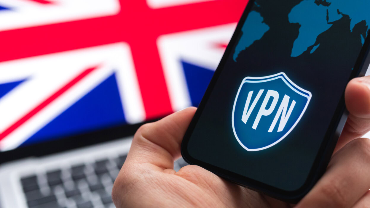 VPN w Wielkiej Brytanii Bezpieczny i bezpieczny internet Prywatność Ręka z telefonem komórkowym i aplikacją VPN Flaga i laptop na zdjęciu w tle