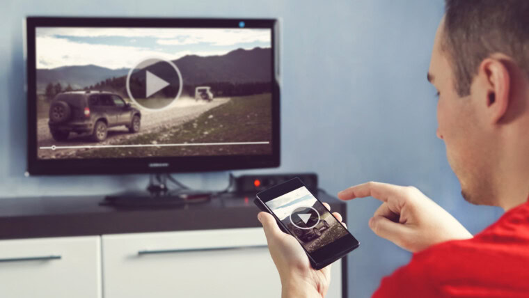 Mężczyzna ze smartfonem podłączonym do telewizora Oglądanie wideo w domu przesyłanie wideo z telefonu na ekran telewizora Nowoczesne gadżety Przesyłanie informacji między urządzeniami przez wifi