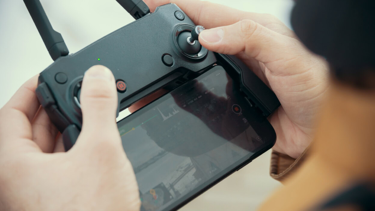 Mężczyzna trzymający pilota do drona śledzącego lot drona