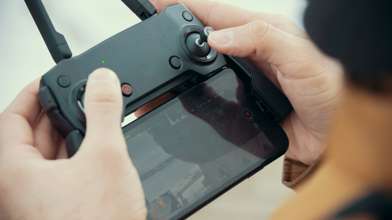 Mężczyzna trzymający pilota do drona śledzącego lot drona