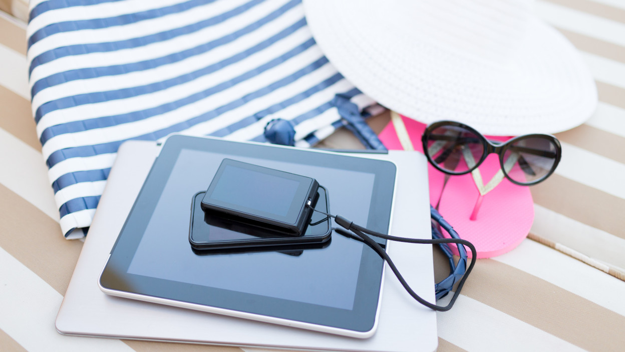 koncepcja plaży, lata, wakacji i technologii - zbliżenie tabletu, notebooka, smartfona i letnich akcesoriów na plaży