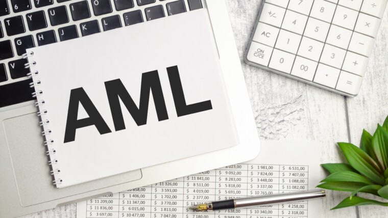 Tekst AML AntiMoney Laundering na notatniku i laptopie na drewnianym tle