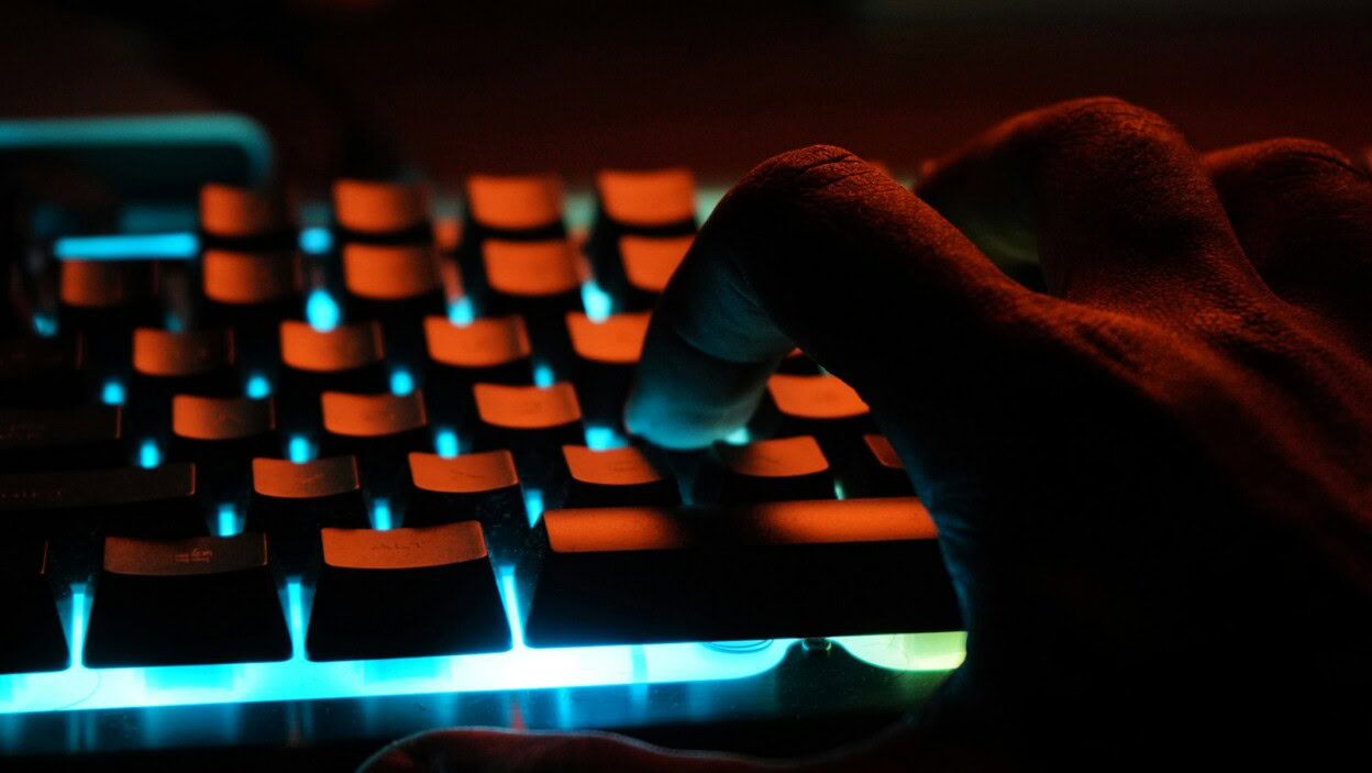 persons hand on blue lighted computer keyboard