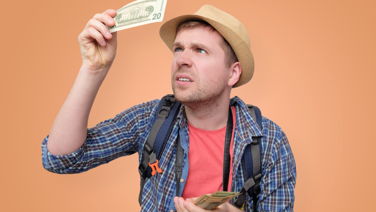Turysta w kapeluszu trzyma banknot dolarowy, sprawdzając go
