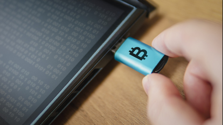 Hardwarowy portfel dla kryptowaluty podłączony do laptopa w ręku człowieka zimny sposób przechowywania kryptowalut na przenośnym nośniku jest sposobem ochrony oszczędności Bezpieczny offline portfel Bitcoin na dysku flash