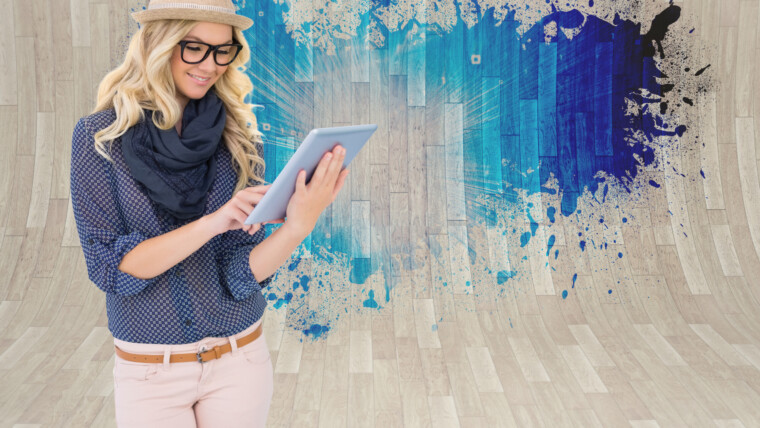 Uśmiechnięta modna blondynka za pomocą komputera typu tablet przed pluskiem pokazującym niebieskie światło