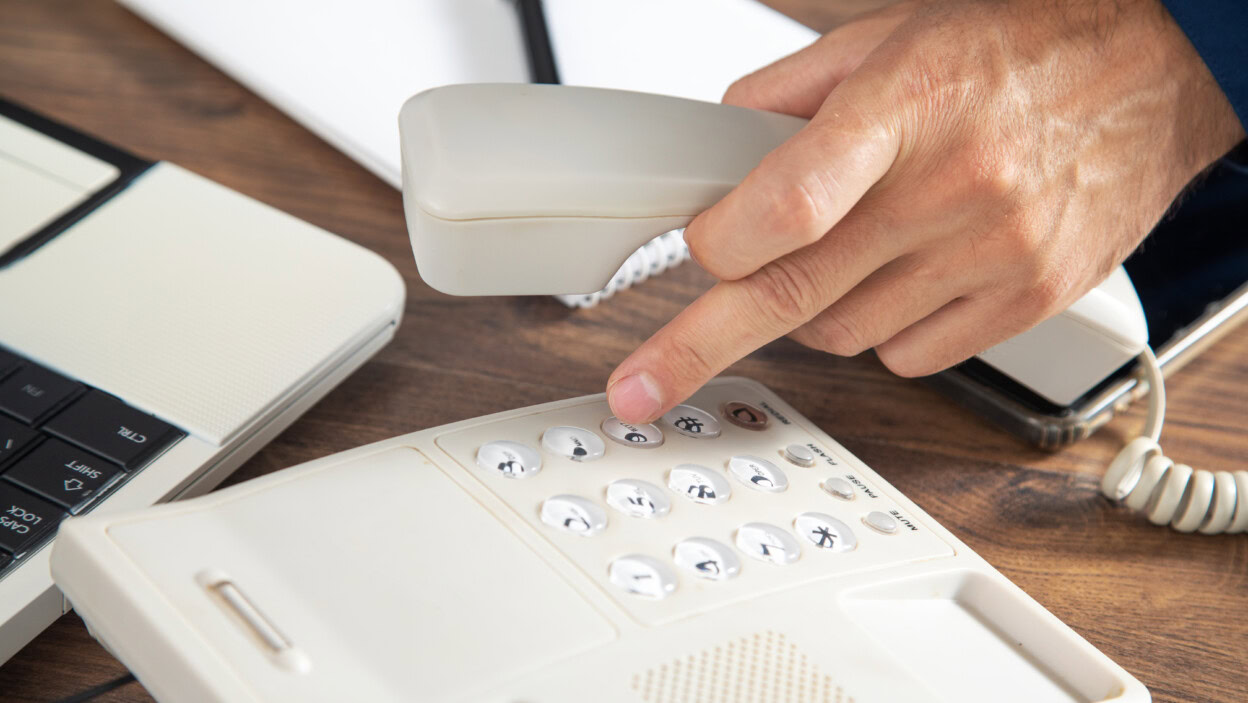 Biznesmen posiadający słuchawkę telefonu przy biurowym stole
