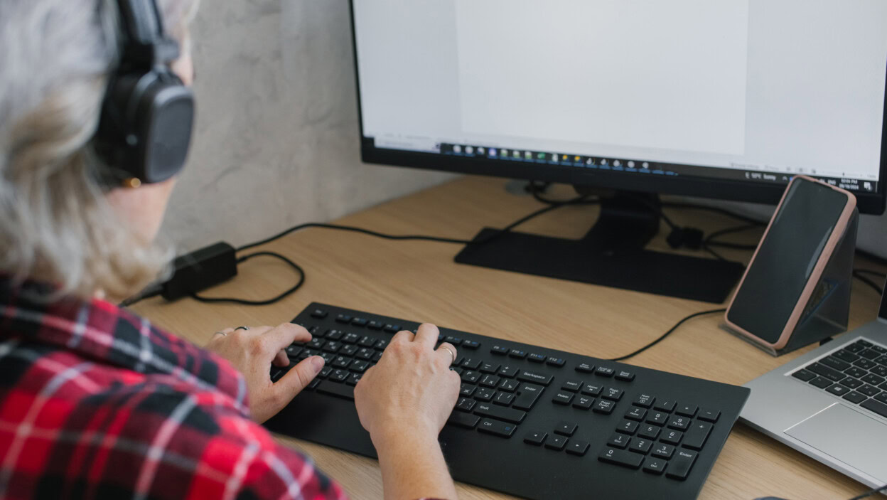 Kobieta z słuchawkami używająca komputera przy biurku