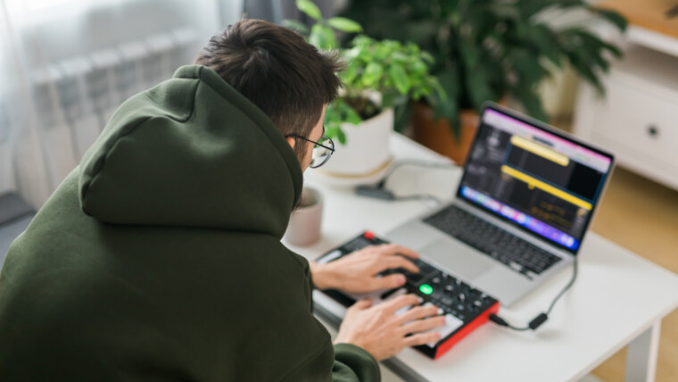 Mężczyzna producent muzyczny lub aranżer używający laptopa i klawiatury midi oraz innego sprzętu audio do tworzenia muzyki w domowym studiu Tworzenie beatów i aranżacja treści audio oraz komponowanie koncepcji utworu