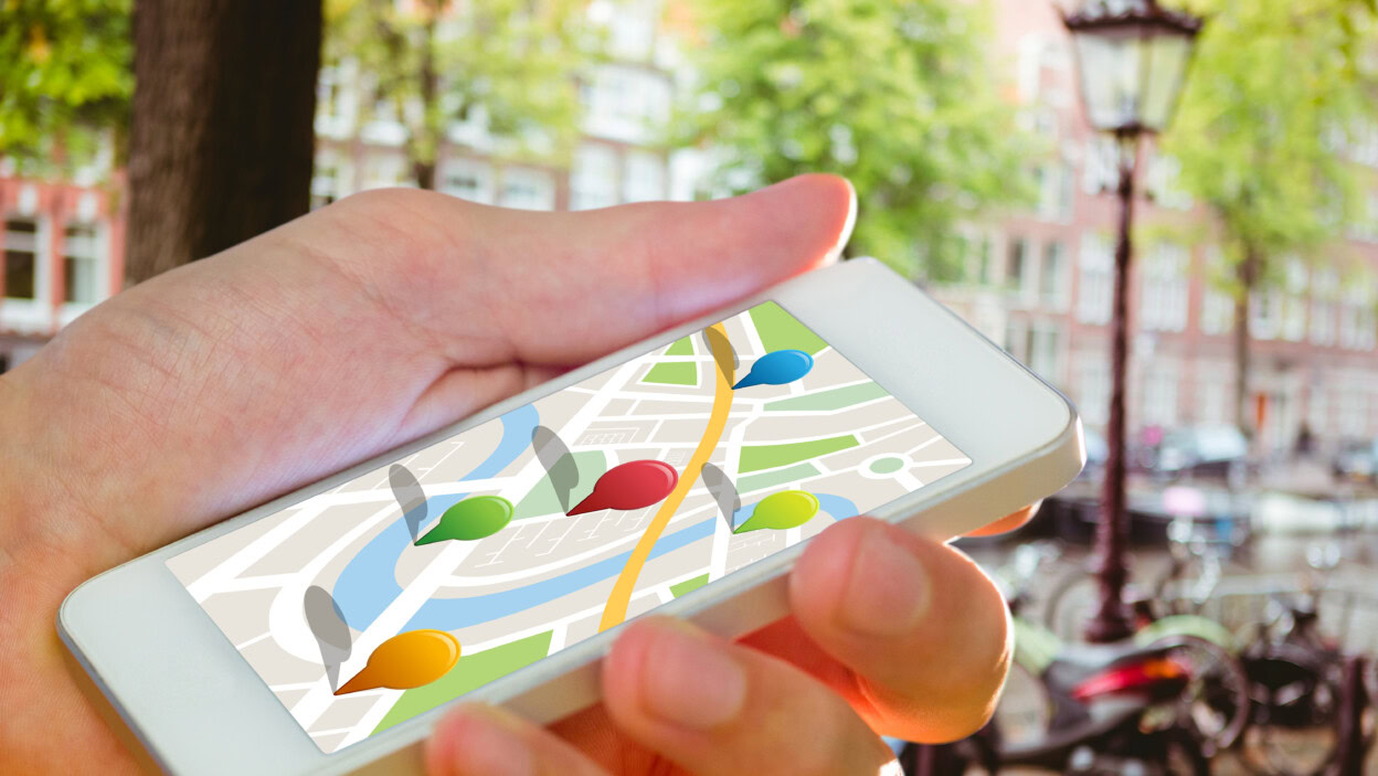 Mężczyzna używający aplikacji mapy na telefonie przed kanałem w amsterdamie