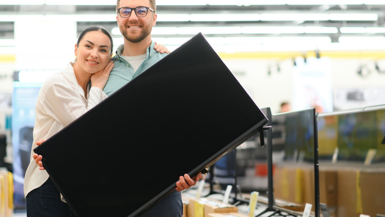 Młoda para wybiera telewizor plazmowy w sklepie z sprzętem domowym, elektroniką i gadżetami Kupowanie nowego telewizora w dniu wyprzedaży