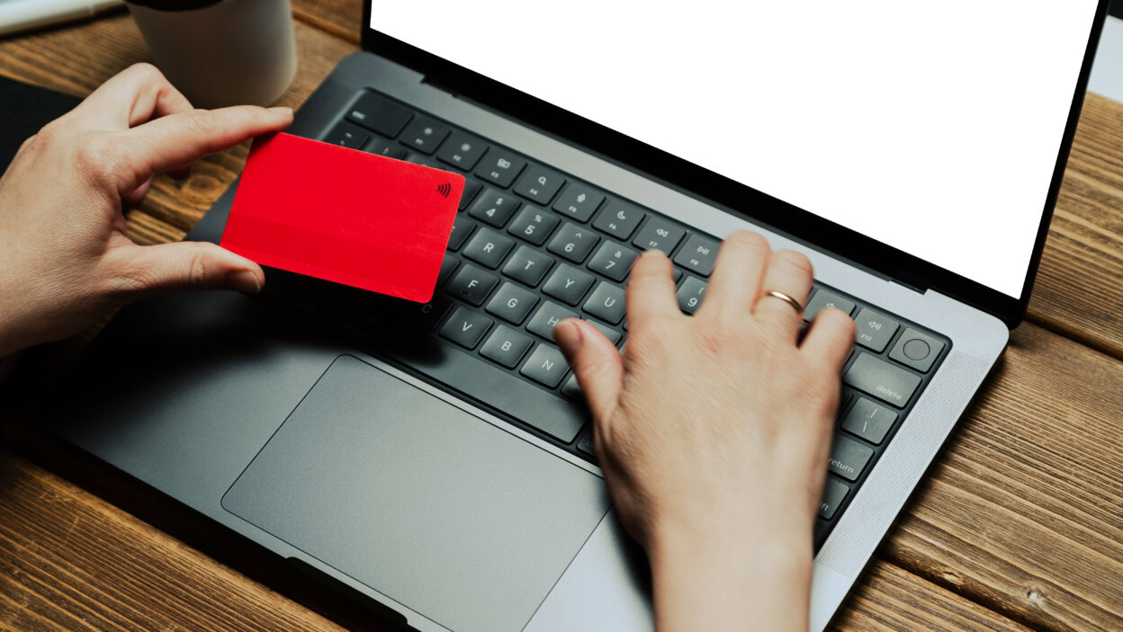 Person using credit card for online shopping on laptop keyboard