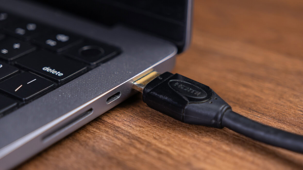 HDMI cable connected to a laptop port on a wooden desk symbolizing digital connectivity and multimedia data transfer for a modern workspace