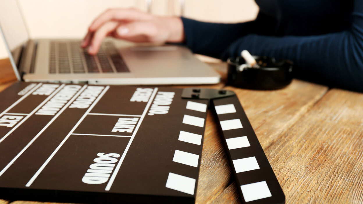 Ręce scenarzystki pracujące na laptopie przy biurku na tle szafy