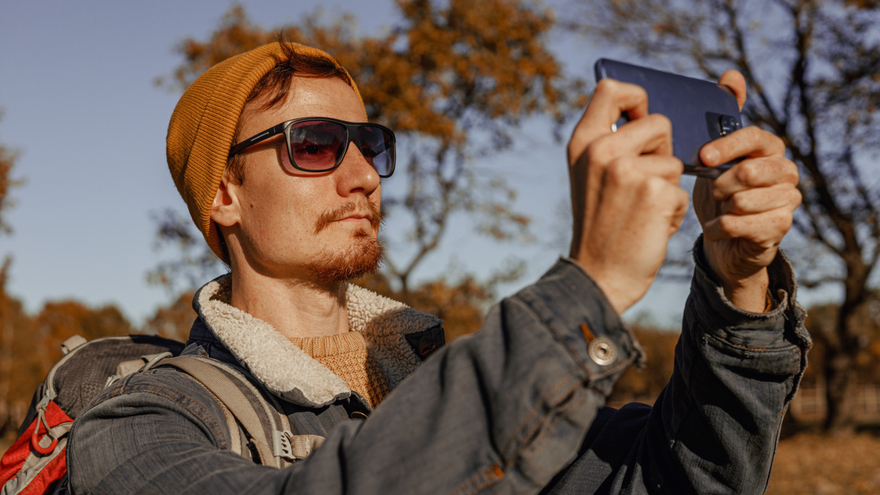 Hiker Capturing Autumn Scenery with Smartphone