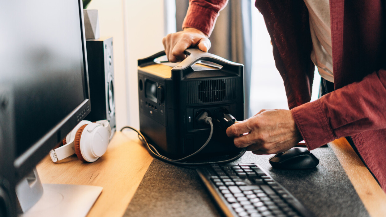 Freelancer man using charging station at home white blackout