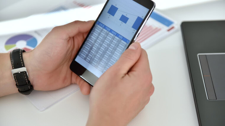 Biznesmen sprawdza raport biznesowy na papierze i smartfonie
