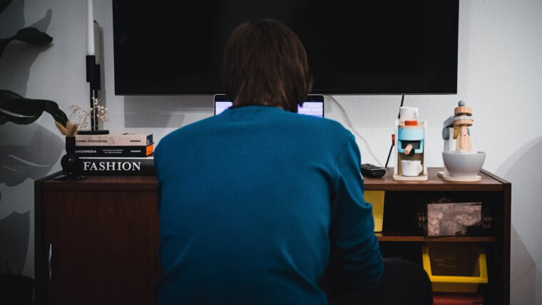 a person sitting at a desk in front of a television
