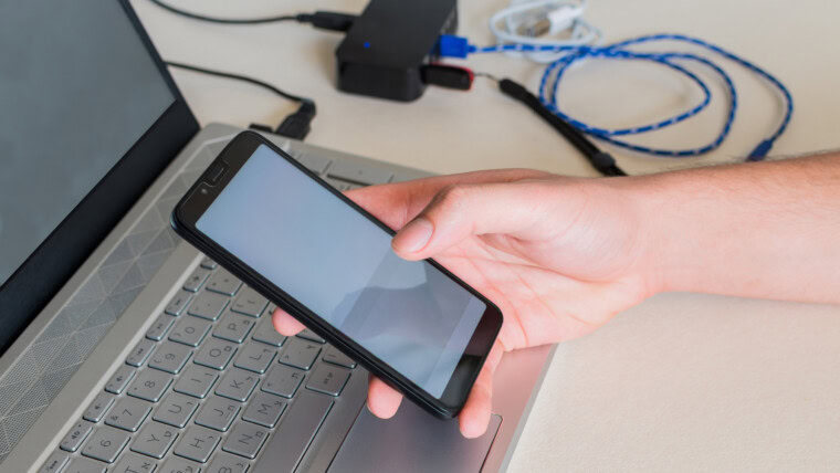 Męskie ręki sprawdza telefon komórkowego obok laptopa na biurku Selekcyjna ostrość